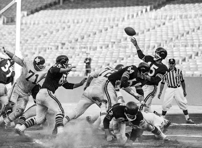 Raiders quarterback Tom Flores throws a pass as he's hit during a 1961 game against the Dallas Texans